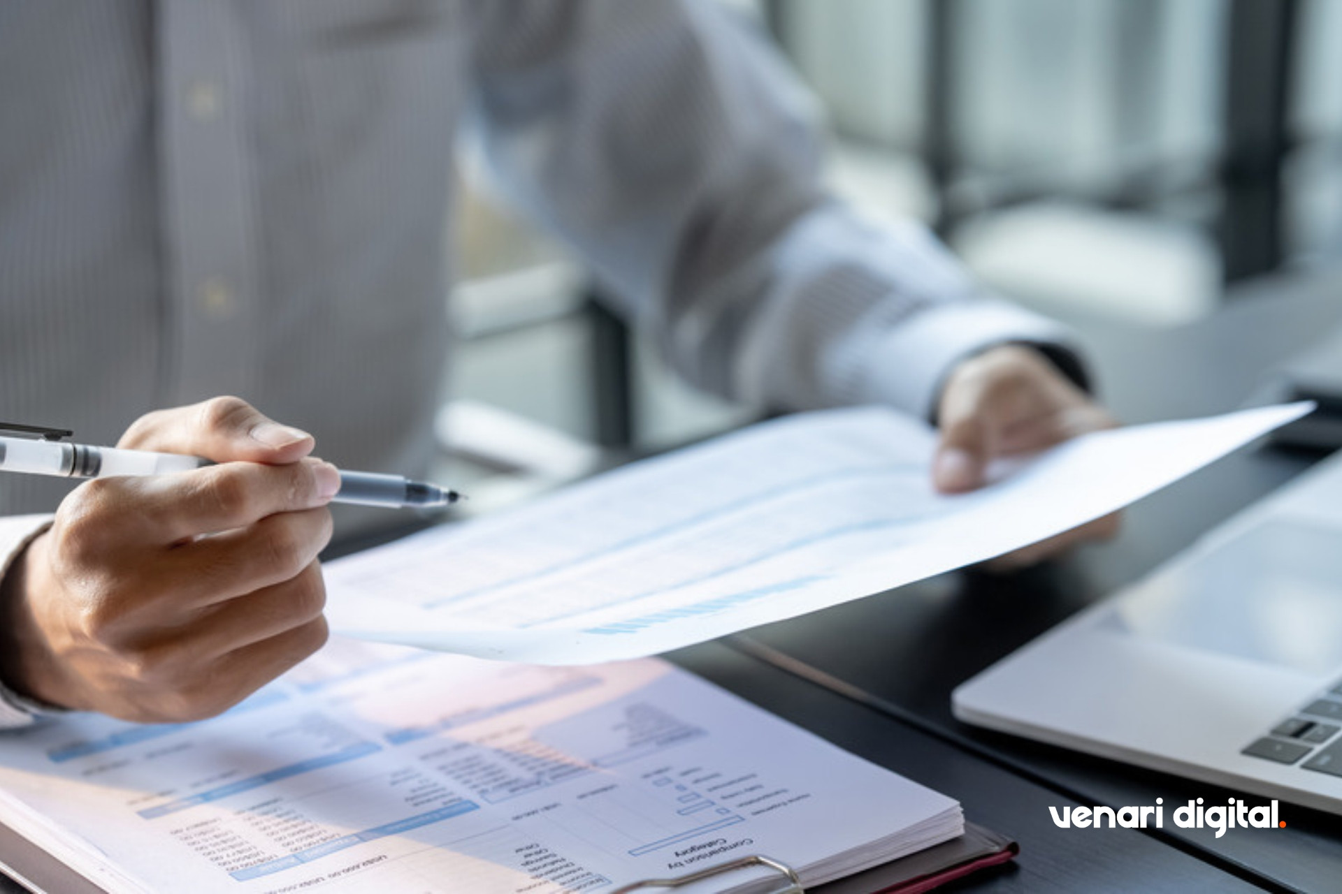 Hands reviewing printed financial report pages at a desk